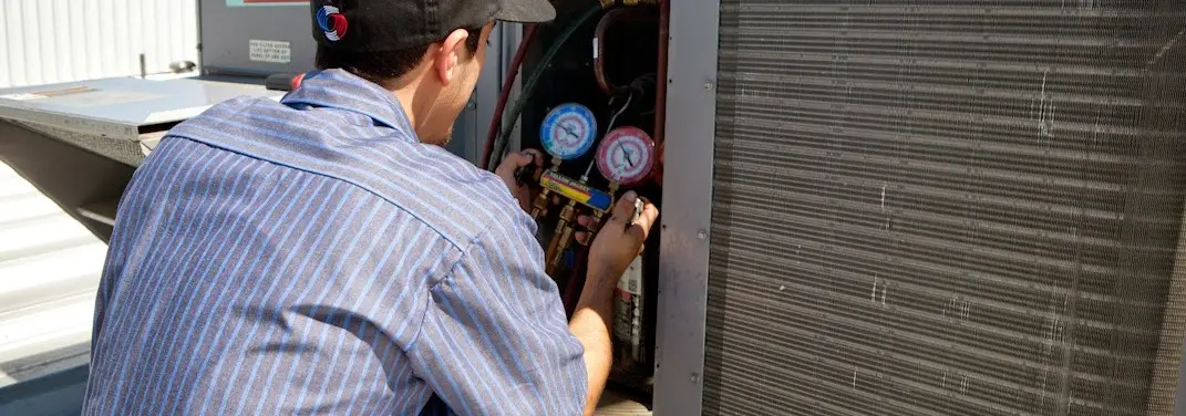 HVAC technician servicing a condenser unit in Oak Grove